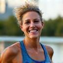 Happy woman in her 40s jogging by the Cumberland River Greenway in Nashville, smiling vibrantly, representing sustainable weight management.